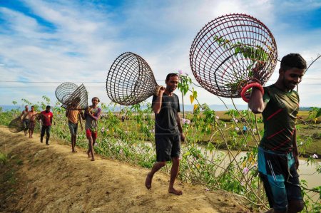Photo for 28 November 2023 Sylhet-Bangladesh: Rural people armed with Bamboo fish traps and Net take parts to celebrating in a 200 years winter fishing festival at the jofra beel of gasbari union of Kanaighat upazila of Sylhet, Bangladesh - Royalty Free Image