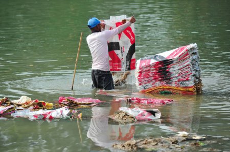 Foto de 10 de diciembre de 2023 Sylhet-Bangladesh: Los trabajadores están arriesgando sus vidas para lavar bolsas de cemento en el agua del río Surma en Sylhet, Bangladesh. Además, ya que está perjudicando su salud a largo plazo - Imagen libre de derechos