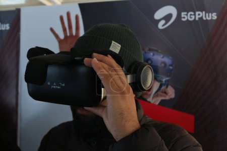 Téléchargez les photos : 12 décembre 2023, Srinagar Cachemire, Inde : Un homme regarde une vidéo sur un casque de réalité virtuelle pendant la 5G en direct plus l'expérience à Srinagar. Airtel a annoncé le lancement de ses services 5G de pointe - en image libre de droit