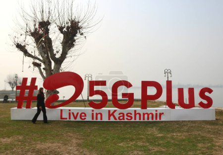Téléchargez les photos : 12 décembre 2023, Srinagar Cachemire, Inde : Une femme passe devant # Airtel5Gplus sur les rives du lac Dal lors d'une expérience en direct 5G plus à Srinagar. Airtel a annoncé le lancement de ses services 5G de pointe - en image libre de droit