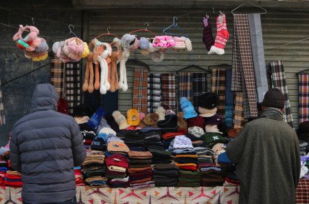 Téléchargez les photos : 13 décembre 2023, Srinagar Cachemire, Inde : Les gens achètent des casquettes d'hiver et d'autres articles dans un marché à Srinagar. Avec l'arrivée de l'hiver ordinaire Cachemiris commencer à se préparer pour le temps rude, l'achat de pulls, vestes et autres vêtements chauds - en image libre de droit