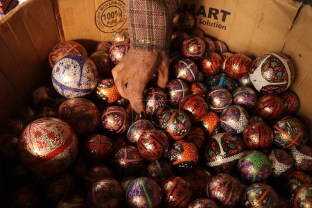 Foto de 16 de diciembre de 2023, Srinagar Cachemira, India: Los adornos de Navidad están listos en el taller antes de enviarlos al mercado antes de las celebraciones navideñas en Srinagar. Los artesanos dicen que los artículos de Navidad están hechos de papier-mache y se envían t - Imagen libre de derechos