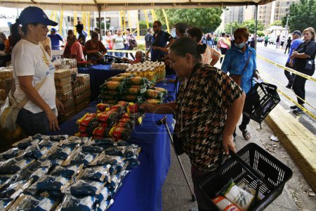 Foto de 18 de diciembre de 2023, San Francisco, Venezuela: Los venezolanos se alinean para comprar alimentos este lunes durante el programa de caridad Popular Markets con el objetivo de beneficiar a miles de familias con la venta de 300 toneladas de alimentos de la canasta básica - Imagen libre de derechos