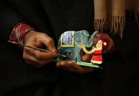 Foto de 16 de diciembre de 2023, Srinagar Cachemira, India: Un artesano cachemir pinta artículos de regalo de Navidad en el taller antes de enviarlos al mercado antes de las celebraciones navideñas en Srinagar. Los artesanos dicen que los artículos de Navidad están hechos de papier-mac - Imagen libre de derechos