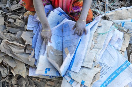 Téléchargez les photos : 19 décembre 2023 Sylhet-Bangladesh : Un jeune garçon avec sa mère qui travaille pour un revenu supplémentaire pour sa famille risque sa vie en travaillant dans la poussière des sacs de ciment près de la rivière Surma à Sylhet, Bangladesh - en image libre de droit