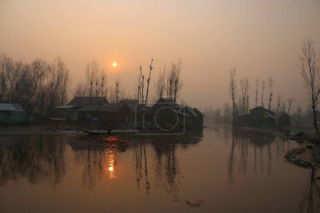 Téléchargez les photos : 21 décembre 2023, Srinagar Cachemire, Inde : Un homme conduit un bateau sur les eaux du lac dal à Srinagar. La période d'hiver la plus dure de 40 jours Chillai-Kalan, commence au Cachemire jeudi - en image libre de droit