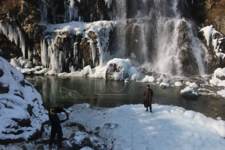 Foto de 21 de diciembre de 2023, Srinagar Cachemira, India: Los visitantes toman fotos cerca de la cascada congelada en el área de Drung de Tangmarg, al norte de Srinagar. El período de invierno más duro de 40 días Chillai-Kalan, comienza en Cachemira el jueves - Imagen libre de derechos