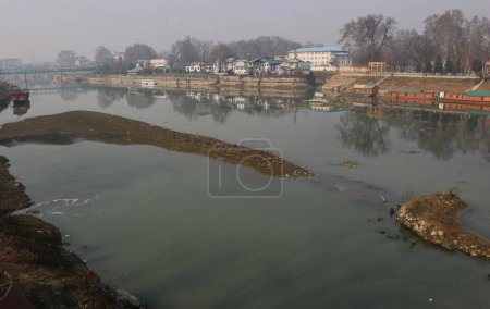Foto de 15 de enero de 2024, Srinagar Cachemira, India: Vista de una porción seca del río Jhelum en Srinagar. El invierno seco prolongado deja el río Jhelum en el punto más bajo histórico, poniendo en peligro las casas flotantes y decepcionantes esquiadores en Gulmarg. - Imagen libre de derechos