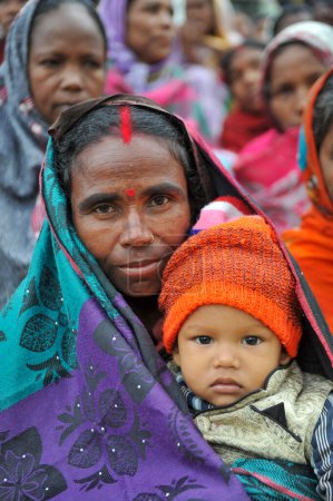 Téléchargez les photos : 17 janvier 2024 Sylhet-Bangladesh : Un tout-petit sur les genoux d'un gardien dans la matinée froide dans les locaux du Tarapur Tea Garden. Les enfants et les personnes âgées souffrent de la sévérité croissante de l'hiver à Sylhet. - en image libre de droit