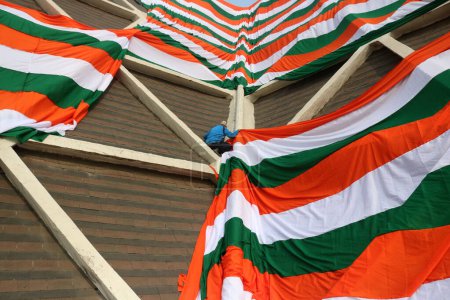 Téléchargez les photos : 23 janvier 2024, Srinagar Cachemire, Inde : Des employés du gouvernement drapent la périphérie d'un stade intérieur avec un géant indien tri-couleur avant la fête de la République indienne à Srinagar - en image libre de droit