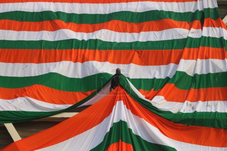 Téléchargez les photos : 23 janvier 2024, Srinagar Cachemire, Inde : Un employé du gouvernement drape la périphérie d'un stade intérieur avec un géant indien tri-couleur avant la fête de la République indienne à Srinagar - en image libre de droit