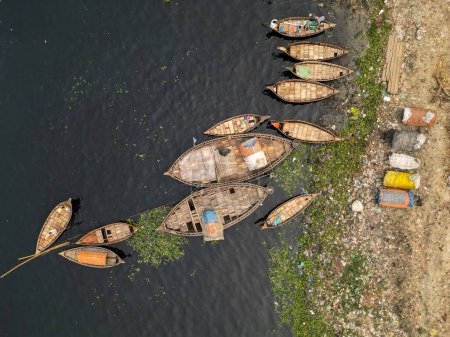 Foto de 30 de enero de 2024, Dhaka, Bangladesh: Vista aérea de barcos de pasajeros de madera a lo largo del puerto del río Buriganga. Los barcos, adornados con coloridas alfombras estampadas, transportan a los trabajadores desde las afueras de la ciudad a su trabajo. - Imagen libre de derechos