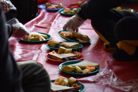 Téléchargez les photos : 19 mars 2024, Srinagar, Inde : Les musulmans du Cachemire leur offrent de la nourriture pour rompre leur jeûne, devant une mosquée pendant le mois sacré du Ramadan - en image libre de droit