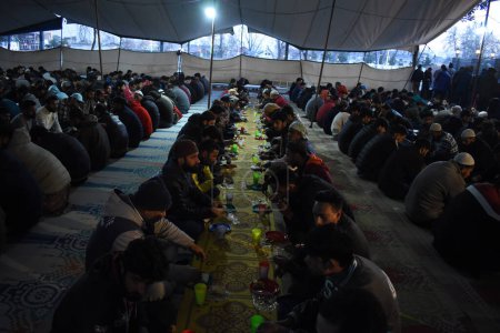 Téléchargez les photos : 19 mars 2024, Srinagar, Inde : Les musulmans du Cachemire rompent leur jeûne devant une mosquée pendant le mois sacré du Ramadan. Masjid-e-Bilal (RDA) à Srinagar - en image libre de droit