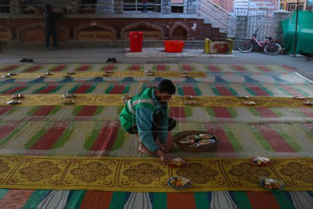 Téléchargez les photos : 19 mars 2024, Srinagar, Inde : Un homme reçoit de la nourriture pour les gens rompre leur jeûne, devant une mosquée pendant le mois sacré du Ramadan - en image libre de droit