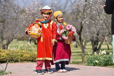 Photo for March 20, 2024, Srinagar India: Two children are seen across the Almond blossom trees early spring across Badawari garden, the garden is very popular at the end of winter and the beginning of spring - Royalty Free Image