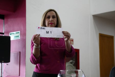Téléchargez les photos : 22 mars 2024, Mexico, Mexique : Une hôtesse montre le rôle de la tombola électorale lors de la session publique de la Table des représentants des débats présidentiels - en image libre de droit