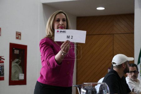 Téléchargez les photos : 22 mars 2024, Mexico, Mexique : Une hôtesse montre le rôle de la tombola électorale lors de la session publique de la Table des représentants des débats présidentiels - en image libre de droit