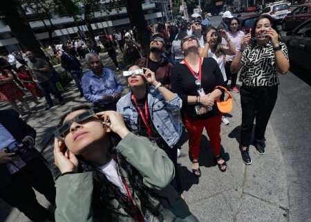 Foto de 9 de abril de 2024, Ciudad de México, México: Gente de la Ciudad de México se reunió en las cercanías del Ángel de la Independencia, para poder observar el eclipse parcial del sol, usaron lentes especiales - Imagen libre de derechos