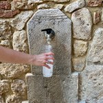 Refilling a plastic water bottle from outdoors on the street in the Sarteano an old Italian city in Tuscany. High-quality photo. 