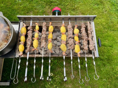 Photo for Automatic roasted meat and potatoes cooked at the barbecue with smoke - Royalty Free Image
