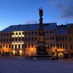 Teplice, Czech Republic - 12.02.2021: The snowy square at the evening, the hotel, the plague pole. High quality photo