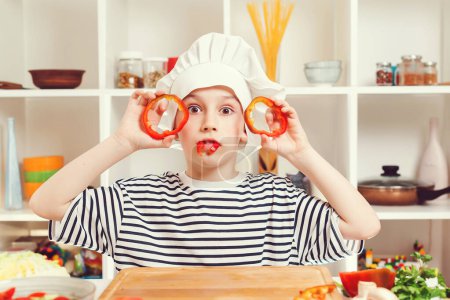 Photo for Chef boy at cooking classes. Cute little chef having fun at kitchen. Future profession. Chef cutting pepper for salad. Boy wearing chef hat. - Royalty Free Image