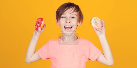 Photo for Happy cute boy played with donuts on yellow background wall. Kid enjoying sweets. Birthday party. Tasty food for kids. Colored donuts. Cute boy showing donuts, over yellow wall. Fashion, people, lifestyle. - Royalty Free Image