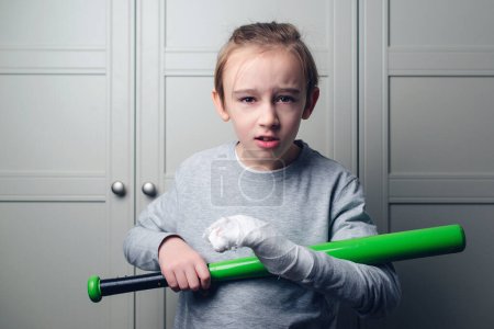 Téléchargez les photos : Boy with a broken arm in plaster holding baseball bat. Kid with broken hand after training. Sport time and healthcare. Health, lifestyle and sport concept. - en image libre de droit
