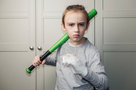 Photo for Boy with a broken arm in plaster holding baseball bat. Kid with broken hand after training. Sport time and healthcare. Health, lifestyle and sport concept. - Royalty Free Image