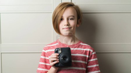 Téléchargez les photos : Cute boy taking selfe with photo camera. Stylish kid over grey background. Child with fun emotion and expreshion. Fashion and technology. - en image libre de droit