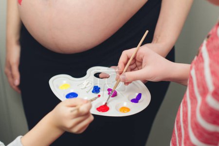 Photo for Baby birth expecting time and belly painting. Happy children and pregnant mom having fun together at home. Family, healthy pregnancy and baby birth. Happy kids painting pregnant belly their mother. - Royalty Free Image