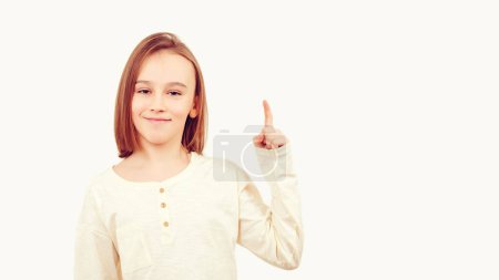 Photo for Young teen boy with long hair posing at studio. Guy pointing up at empty space. Boy gesturing new idea. Emotional portrait of happy teen boy over white background with copy space. - Royalty Free Image