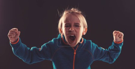 Photo for Angry boy shouting in dark. Kid mad shouting and yelling with aggressive expression and arms raised. Frustration concept. - Royalty Free Image