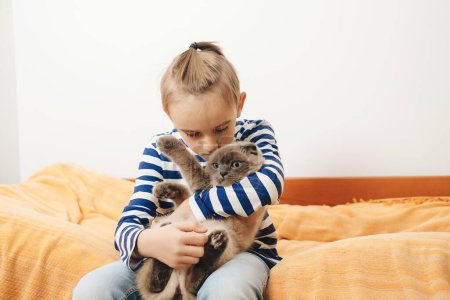 Téléchargez les photos : Mignon garçon joue avec un chat à la maison. Joyeux gamin embrassant son chat. Garçon relaxant sur le lit avec animal de compagnie. Enfance, véritable amitié et animal domestique. - en image libre de droit