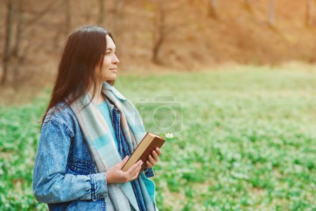 Photo for Woman enjoying spring day at nature. Lifestyle, people and spring time. Young woman with book on the walk. Time for reading. Reading book concept. - Royalty Free Image