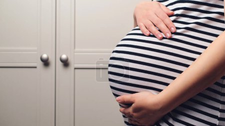 Photo for Baby expectation. Pregnancy, maternity, preparation and expectation concept. Woman dreaming about child. Background with copy space. Pregnant woman holdig hands on belly, closeup. Pregnant woman's belly. - Royalty Free Image