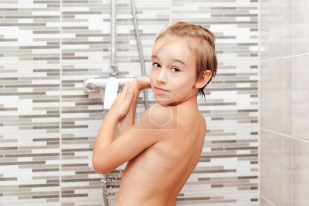 Foto de Lindo niño lavándose en la ducha. Feliz chico teniendo una ducha en el baño. Infancia saludable, concepto de estilo de vida. - Imagen libre de derechos