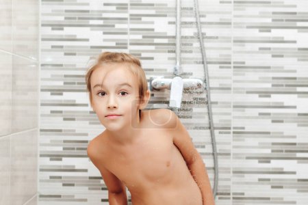 Foto de Chico lavándose en la ducha. Una infancia saludable, un concepto de estilo de vida. Niño feliz teniendo una ducha en el baño. - Imagen libre de derechos