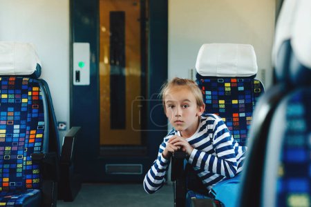 Foto de Lindo chico sentado en el tren eléctrico. Un niño viajando en el tren. Infancia, vacaciones en familia, estilo de vida. - Imagen libre de derechos