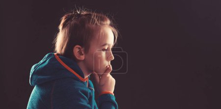 Photo for Stressed boy over black background, copy space. Childhood, bulling and family concept. Sad young boy thinking about his problems. Afraid child sitting quiet in dark. Young boy suffering from anxiety. - Royalty Free Image