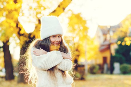 Foto de Chica feliz caminando en el parque de otoño. Lindo niño sonriendo y posando al aire libre. Niña usando suéter de punto caliente. Otoño niños moda, estilo de vida. - Imagen libre de derechos
