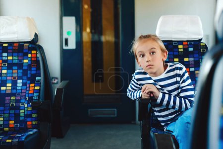 Photo for Cute boy sitting in commuter electric train. Little kid traveling on the train. Childhood, family vacation, lifestyle. - Royalty Free Image