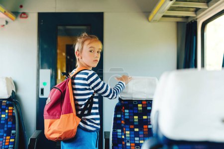 Photo for Little passenger standing inside train. Train arrival, departure. Small kid leaving wagon. Cute preteen boy getting off train. - Royalty Free Image