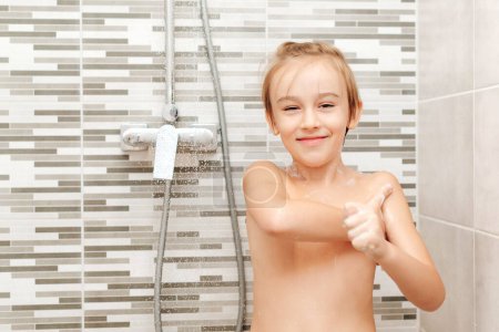 Téléchargez les photos : Mignon enfant se laver sous la douche. Joyeux garçon qui prend une douche dans la salle de bain. Enfance saine, concept de mode de vie. - en image libre de droit