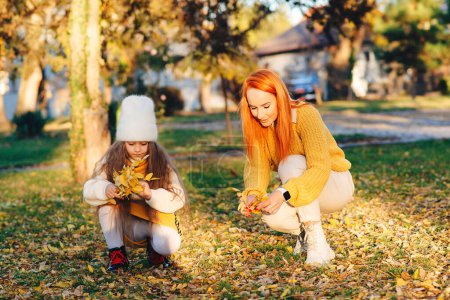 Photo for Happy family enjoying autumn day together. Family autumn walk. Autumn holidays, lifestyle, childhood. Mother and child girl playing with autumn leaves. - Royalty Free Image