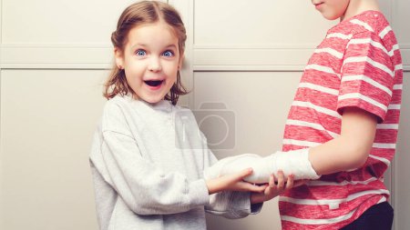 Photo for Child girl holding his brother's broken arm. Boy holds hand bent broken arm cast on his arm. Girl is in shock - Royalty Free Image