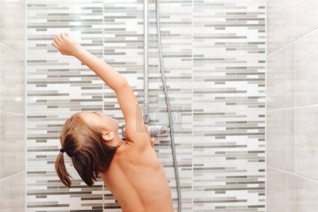 Téléchargez les photos : Garçon se laver sous la douche. Enfance saine, concept de mode de vie. Enfant heureux ayant une douche dans la salle de bain. - en image libre de droit