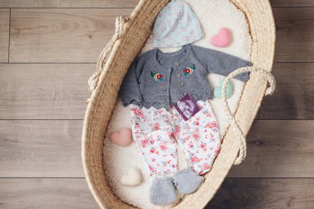Photo for Basket with baby clothes. Wicker basket with baby stuff and accessories for newborn, top view. - Royalty Free Image