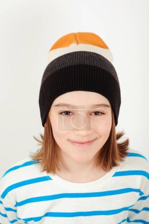 Téléchargez les photos : Joli garçon portant un élégant chapeau en laine. Portrait du visage d'un gamin de onze ans. Enfant posant sur fond blanc. - en image libre de droit